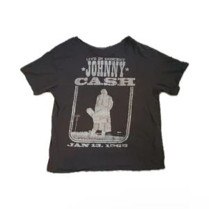 Johnny Cash t-shirt - Mörkgrå t-shirt med stort vintageinspirerat Johnny Cash-tryck på framsidan. Trycket har texten 'Live in Concert Johnny Cash Jan 13, 1968' och en siluett av artisten. Klassisk passform och rund hals, perfekt för dig som gillar musik och retrostil. Tröjan är klipp vid kragen. 🦇