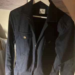 Mörkblå overshirt John Henric  - Mörkblå overshirt från John Henric. Mycket bra skick och inte använd så många gånger. Annars mycket bra skick. Inga defekter eller så. Passar perfekt till hösten som kommer nu eller våren. Nypris runt 1500kr, mitt pris 300kr. Kontakta mig om du har frågor✅