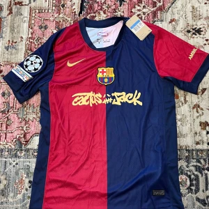 FC Barcelona Raphinha 11 Nike fotbollströja - Säljer en FC Barcelona matchtröja från Nike med Raphinha 11 på ryggen. Tröjan är kortärmad, i blått och rött med gula detaljer och klubbmärke på bröstet. Tillverkad i Dri-FIT material för bästa komfort. Champions League-märke på ärmen.