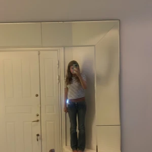 Replay bootcut jeans med detaljer - Säljer ett par blå Replay jeans med bootcut passform och låg midja. Jeansen har slitningar, snygga nitar och stenar på bakfickan samt klassisk Replay-lapp i läder baktill. Perfekta för dig som gillar en avslappnad men trendig look.