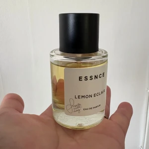 ESSNCE Lemon Eclair parfym - Fräsch parfym från ESSNCE med doften Lemon Eclair. Flaskan är rund och genomskinlig med gul vätska och har en stilren svart kork. Etiketten är vit med svart text och minimalistisk design. Perfekt för dig som gillar citrusdofter. Går inte att köpa längre då det var en limited edition. Testad några gånger 