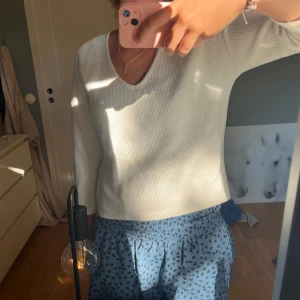 Vit stickad v-ringad tröja  - Supermjuk och enkel vit stickad tröja med v-ringning och lång ärm. Stilren och passar till allt, med en lite lösare passform för chill vibe.