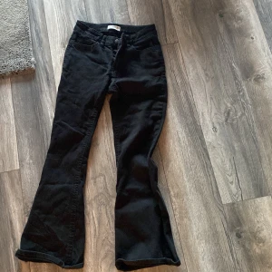 Svarta bootcut byxor från Lindex - Svarta byxor från Lindex i bootcut-modell med klassisk femficksdesign. Byxorna har normal passform och är tillverkade i ett mjukt bomullstyg med lite stretch. Perfekta för dig som gillar en tidlös look med lite utsvängda ben.