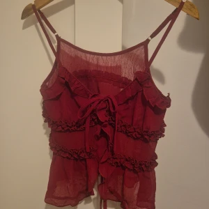 Vinröd volangig linnetopp - Supersöt vinröd linnetopp från SHEIN med tunna axelband, volangdetaljer och knyt framtill. Toppens tyg är lätt och transparent, perfekt för lager-på-lager. Rynkade volanger ger en romantisk vibe och toppen är croppad för en trendig look. Köpte den för att ta lite inspiration från den för att göra min egen i skolan! Så jag har inte riktigt anvönt den. 