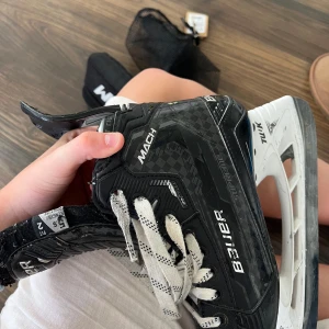 Bauer Supreme Mach skridskor svart/vit - Säljer ett par Bauer Supreme Mach skridskor i svart med vita detaljer och snörning. Skridskorna har en robust och sportig design med kolfibermönster och vit sula. Perfekta för dig som vill ha grym kontroll och stil på isen. Jag köpte skridskorna för 8999kr men säljer för 2500 de är jätte bra skick och dem är endast använda en säsong!