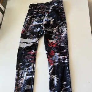 Stronger leggings med abstrakt mönster - Snygga leggings från Stronger med ett coolt abstrakt mönster i svart, vitt och rött. De har hög midja och är tillverkade i stretchigt syntetmaterial som passar perfekt för träning. Loggan syns diskret på höften. 