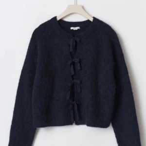 Mörkblå kofta med rosetter  - Snygg och fluffig mörkblå kofta med långa ärmar och flera knytband framtill istället för knappar. Koftan har en rund halsringning och är gjord i ett mjukt, stickat material som känns både trendigt och mysigt. Passar till allt! 💗