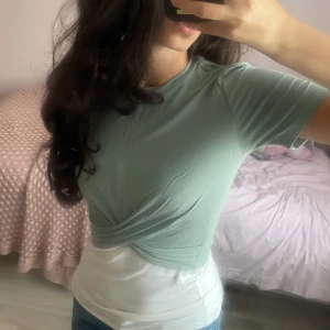 Mintgrön omlott-topp  - Snygg topp i mintgrönt med omlott-detalj över magen. T-shirten har rund halsringning och korta ärmar. Jättefin med ett vitt linne under. Pris kan diskuteras 💕