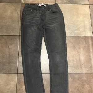 Levi's 512 Slim Taper svarta jeans - Svarta Levi's 512 Slim Taper jeans med klassisk femficksdesign och smal passform. Jeansen har en snygg tvättad look och är tillverkade i mjukt denimtyg. Perfekta för dig som gillar en modern och stilren vibe.