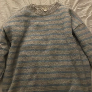 Randig blå och grå tröja Gina Tricot - Mysig stickad tröja från Gina Tricot i storlek 146/152. Tröjan har ett randigt mönster i ljusblått och grått, rund halsringning och långa ärmar. Perfekt för dig som gillar en chill och stilren look.