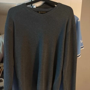 Mörkgrå stickad tröja från Dylan Star - En stilren mörkgrå stickad tröja från Dylan Star i storlek M. Tröjan har rund halsringning och långa ärmar, perfekt för lager-på-lager. Enkel och clean design som funkar till många olika outfits.