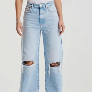 Ljusblå Idun Wide jeans från ginatricot  - Säljer ett par ljusblå jeans från gina med breda ben och hög midja. Jeansen har stora slitningar vid knäna och fransade benslut. Fint skick, använda fåtal gånger. 