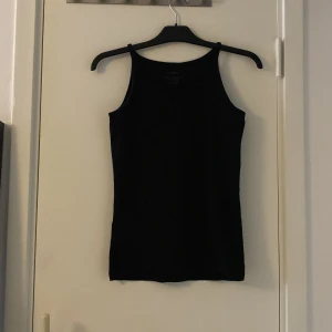 Svart enkel linnetopp - Säljer en svart, stilren linnetopp med smala axelband och rak passform. Perfekt att matcha med jeans eller kjol för en clean look. Mjuk och skön känsla, passar till många outfits.