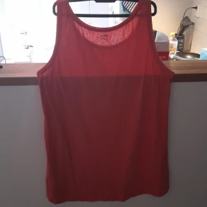 Röd ärmlös linnetopp från Ullared - Enkel och snygg röd linnetopp från Ullared Basic you. Modellen är ärmlös med rund halsringning och har en loose passform. Perfekt för varma dagar eller att styla lager på lager. Tunt och lätt material som känns skönt mot huden.