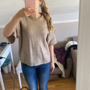 Beige stickad tröja med kort ärm - Säljer en beige stickad tröja med korta, vida ärmar och rund halsringning. Har klippt ärmarna själv.