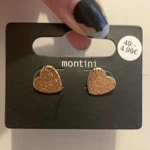 Glittriga hjärtörhängen från Montini - Supersöta örhängen från Montini i form av hjärtan med glittrig yta i guld. Perfekta för att ge din look lite extra shine! Helt oanvända!