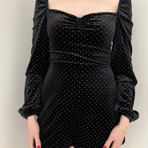 Svart prickig sammetsklänning S - Supersnygg svart sammetsklänning med silvriga prickar, lång puffärm och söt rynkning vid bysten. Klänningen är kort och har en figurnära passform med dragkedja i ryggen. Perfekt för dig som vill sticka ut med en trendig look!