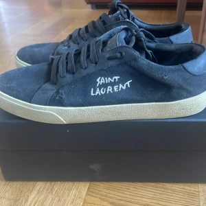 Svarta Saint Laurent sneakers - Säljer nu ett par Saint Laurent skor som även köptes här på plick för ett tag sen. skorna har använts ett fåtal gånger och har inga synliga defekter på utsidan. Däremot en liten skada på insidan av skon som man kan se på sista bilden. De är även lite skitiga men går lätt att tvätta bort. Det mesta ingår som box och ett kort som garanterar att skorna är äkta. Vill få sålt dom ganska snabbt därav priset. Priset är inte hugget i sten. Annars är det bara att kontakta om ni har några frågor!