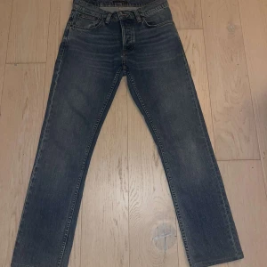 Nudie Jeans Grim Tim True Gold 30/32 - Snygga blå Nudie Jeans i modellen grim tim.  Klassisk femficksdesign, de har slimfit passform. Tillverkade i 99% bomull och 1% elastan för lite stretch. Perfekta för dig som gillar kläder som sitter bra och har en bra passform. De är i mycket bra skick, endast tvättats några gånger. Skriv till mig om ni undrar något😆