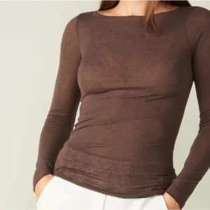 Brun intimissimi - Slimmad brun långärmad topp med rund halsringning. Tunn och mjuk i materialet, perfekt att styla med jeans eller kjol. Enkel och stilren design som passar till många olika looks.