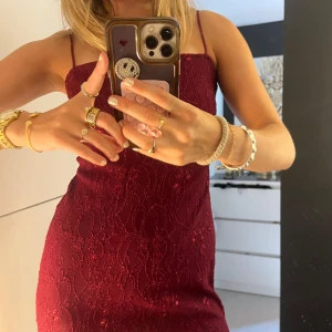 Vinröd balklänning  - Säljer en vinröd långklänning från Windsor med tunna axelband och glittrig spetsdetalj. Jag använde den som balklänning, därför bara använd 1 gång. Klänningen har figurnära passform och är perfekt för dig som vill sticka ut. Materialet är en mix av nylon, lurex och polyester för en lyxig känsla. OBS klänningen har två slitsar på sidorna så benen kan visas :)