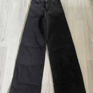Svarta wide jeans från Lindex - Säljer ett par svarta jeans från Lindex i modellen Viola. De har hög midja och breda ben för en riktigt chill och trendig look. Klassisk femficksdesign och tillverkade i bomull. Perfekta till sneakers eller boots.