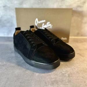 Svarta sneakers från Christian Louboutin - Snygga svarta sneakers från Christian Louboutin i mocka med klassisk röd sula. Skorna har rund tå, svarta snören och diskreta sömdetaljer. Perfekta för dig som vill ha en stilren och lyxig look med en ikonisk touch. Jag har båda storleken 41 och 42