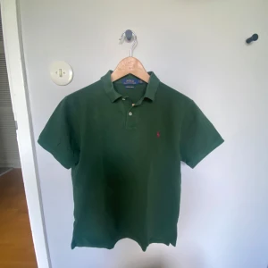 Grön pikétröja Polo Ralph Lauren M - Snygg grön pikétröja från Polo Ralph Lauren i modellen Custom Slim Fit. Den är i storlek M men sitter som en S. Mycket bra skick. Hör av er vid intresse!!