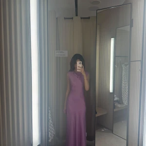 Lila satin Mango klänning  - Säljer en elegant satin lila långklänning med ärmlös design och snygg draperad halsringning. Använd en gång!