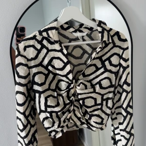 Mönstrade vida byxor i svart och vitt samt topp - Snygga byxor från H&M storlek 40med grafiskt svartvitt mönster. Byxorna har en rak och vid passform, stängs med knapp och dragkedja. Materialet är mjukt och faller snyggt, perfekt för dig som gillar statement-plagg. Tillhörande topp i S