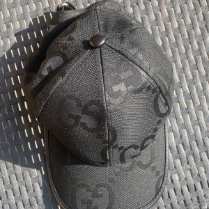 Louis Vuitton rutigt svart bälte - Snyggt bälte från Louis Vuitton med klassiskt rutigt mönster i svart och grått. Bältet har en stor LV-logga i svart metall som spänne och är gjort i skinn med en lyxig känsla. Perfekt accessoar för att lyfta din outfit.