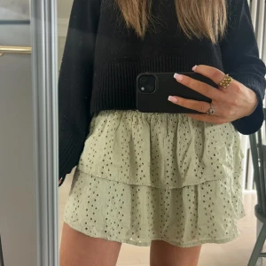 Beige volangkjol med broderade hål - Supersöt beige kortkjol med volanger och broderade hål. Kjolen har resår i midjan och är gjord i ett lätt bomullstyg som känns luftigt och fräscht. Perfekt för varma dagar när du vill ha en chill och trendig look.❤️❤️