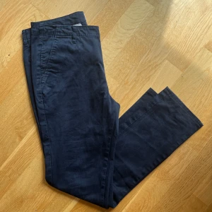 Mörkblå chinos från NN07 New Simon - Snygga mörkblå chinos från NN07, modell New Simon. Skick 9/10 riktigt bra utan syndliga defekter. Nypris ligger runt 1600 men säljs nu för 399kr. Hör av er vid minsta lilla fundering!