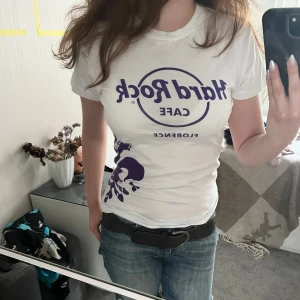 Hard Rock Cafe t-shirt  - Vit t-shirt från Hard Rock Cafe, Florence med lila tryck framtill och stor dekorativ lila lilja med gitarrdetalj på sidan. Storlek Small, skriv vid frågor! 🫶💗