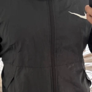 Svarta träningsbyxor från Nike - Svarta träningsbyxor från Nike med klassisk vit swoosh-logga på benet. Byxorna har en sportig look, smal passform och är tillverkade i ett lätt syntetmaterial som andas. Perfekta för gymmet eller löprundan.