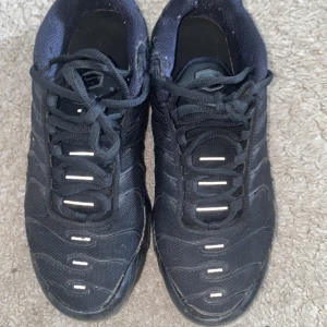 Svarta Nike Air Max Plus sneakers TN - Nike Air Max Plus sneakers i helsvart med gula och röda detaljer under sulan. Ovandelen är i mesh och syntet med vågformade linjer och snörning. Synlig Air Max-dämpning i sulan och TN-logga på hälen. Perfekta för dig som gillar streetwear och sportig stil. För fler frågor och bilder är det bara att skriva de är köpta 8 månader sen! 