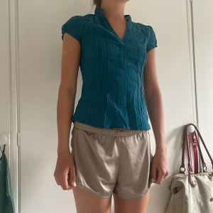 Blå randig blus från H&M - Säljer en blå randig blus från H&M i storlek 32. Blusen har korta ärmar, v-ringning och en liten ståkrage. Materialet är lätt och känns skönt mot huden, perfekt för varmare dagar. Snygg passform som sitter lite figurnära.