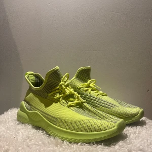 Neongula stickade sneakers - Snygga sneakers i neongult med stickad ovandel och coola detaljer i grått. Skorna har snörning och en chunky, vågformad sula som ger en sportig vibe. Perfekta för dig som vill sticka ut med färg och komfort. Lätta och flexibla, passar till streetwear och träning.