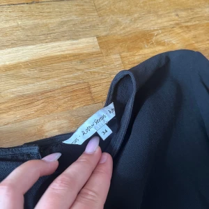 Svart blus från & Other Stories - Stilren svart blus från & Other Stories i storlek 34. Blusen har rund halsringning, långa ärmar och knäppning bak med tre knappar. Tunt, lätt material som ger en snygg och enkel look. Perfekt att matcha med jeans eller kjol.