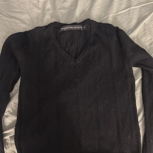 Svart ribbad v-ringad tröja S - Svart långärmad tröja från The Black Label Collection i storlek S. Tröjan har v-ringning och är ribbad för en snygg och stilren look. Perfekt att matcha med jeans eller kjol för en clean outfit.