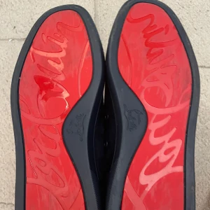 Mörkblå sneakers från Christian Louboutin - Snygga mörkblå sneakers från Christian Louboutin i mocka med klassisk röd sula. De är i ny skick då de är andvända 1 gång till en fest och säljes för att de inte andvänds
