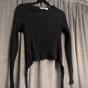 Svart ribbad långärmad topp NA-KD - Svart ribbad långärmad topp från NA-KD i storlek S.  Knytning vid ryggen och väldigt bekväm. Sparsamt använd, de vita små prickarna på armen kommer inte att finnas på tröjan vid köp! 🫶🏻