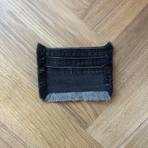 Jeans plånbok  - Fin jeans plånbok med lite stretchigare tyg och fransiga kanter, finns tre fak till kort och är i normal storlek.