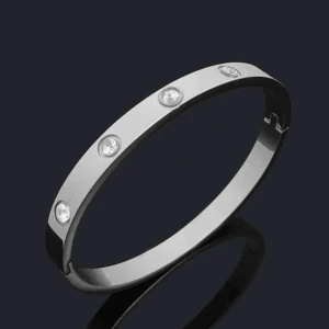Silverfärgat armband med stenar - Stilrent armband i silverfärg med rund form och infattade klara stenar runt om. Armbandet har en slät, blank yta och är perfekt för dig som gillar minimalistisk och modern design. Den har tappat två stenar på baksidan men syns inte. Pris kan diskuteras!