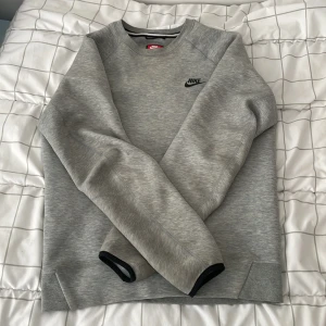 Grå Nike sweatshirt i bomull - Snygg grå sweatshirt från Nike med svart logga på bröstet. Klassisk rund halsringning och långa ärmar. Mjuk och skön bomullsblandning, perfekt för chill eller träning. Enkel och stilren design som funkar till det mesta.