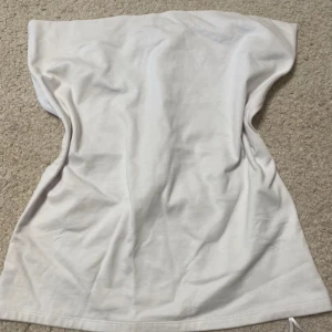 Vit bandeau tubtopp med twistad detalj - Säljer en vit bandeau tubtopp i mjuk bomull. Toppen har en snygg twistad detalj framtill som ger en cool look. Perfekt för dig som gillar minimalistisk stil och vill ha något enkelt men ändå trendigt. Passar till många olika outfits!