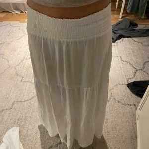 Vit långkjol med smock i midjan - Lång kjol från lager som inte kommit till användning. Den är luftig och skön så perfekt till sommarn och semestern. Kontakta för frågor eller fler bilder!💕