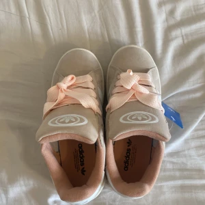 Adidas Campus sneakers beige/rosa - Snygga Adidas Campus sneakers i beige mocka med klassiska vita ränder och ljusrosa detaljer. Skorna har breda rosa snören och vit platt sula. Perfekta för dig som vill ha en clean och trendig look med en touch av färg. Dom va för små för syrran och är helt nya!
