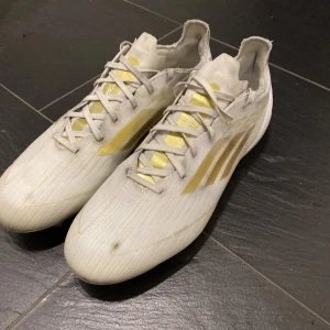 Adidas F50 - Säljer ett par vita Adidas f50 PRO med touch av guldfärgat. Skorna är i bra skick men har tecken på användning kom gärna med bud och tveka inte vid frågor 