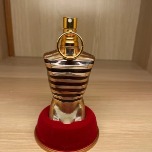 Jean Paul Gaultier Le Male Elixir Eau de Parfum 75ml - Exklusiv herrparfym från Jean Paul Gaultier, Le Male Elixir. Flaskan har en unik kroppsliknande form i guld och brons med svarta ränder. Kommer i en lyxig metallburk med matchande design. Innehåller 65 ml eau de parfum.